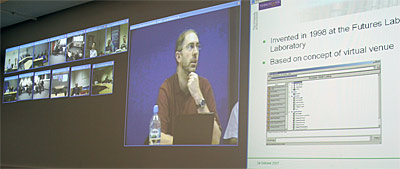 Screens showing participants in the other locations, the presenter, and his current slide